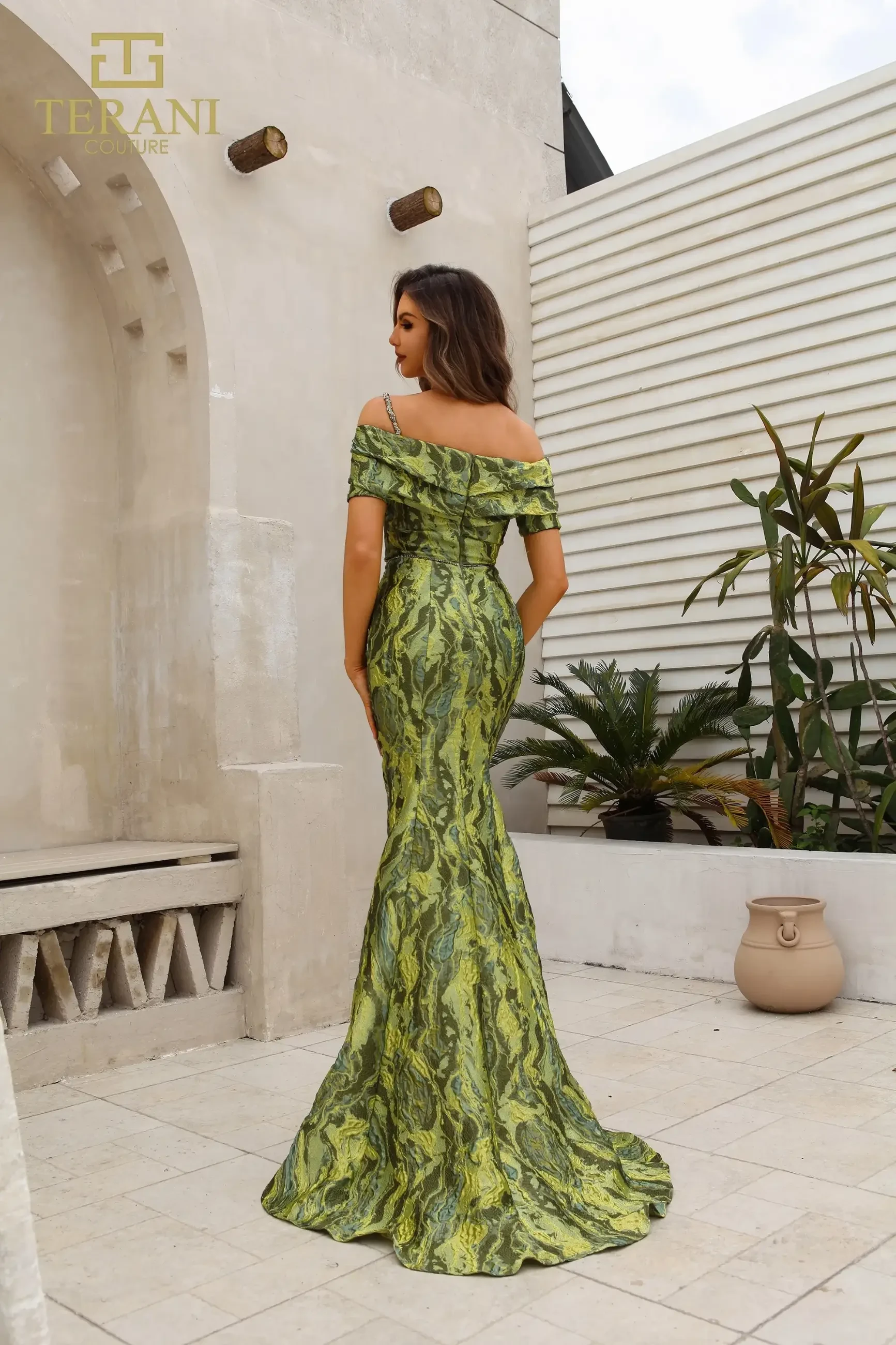 Model is wearing a green multicolor floral sheath dress with an off-the-shoulder neckline, cap sleeves, and premium lava jacquard fabric.