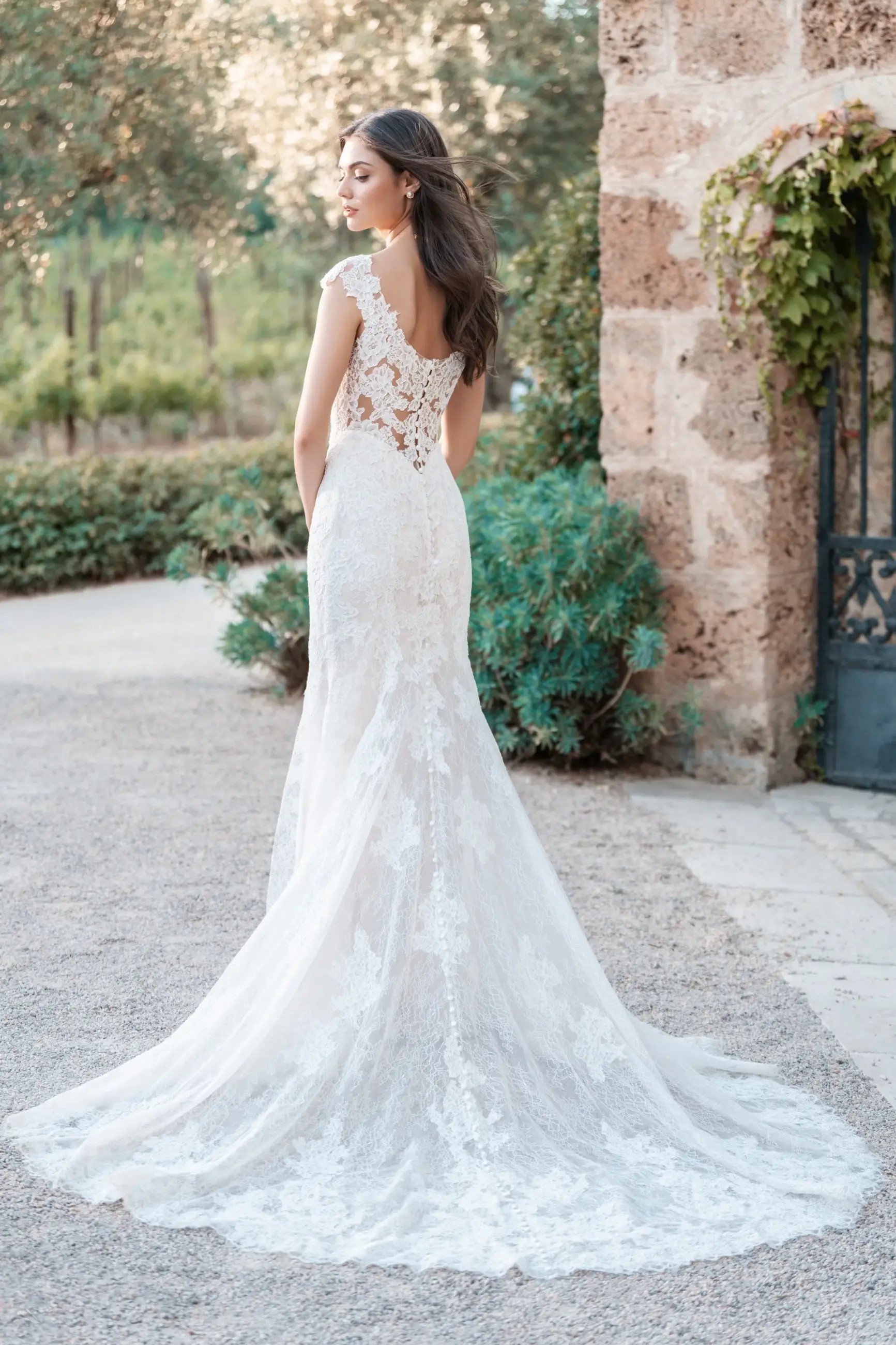 Model is wearing a chantilly lace wedding dress with a tapered neckline and sheath skirt by allure bridals