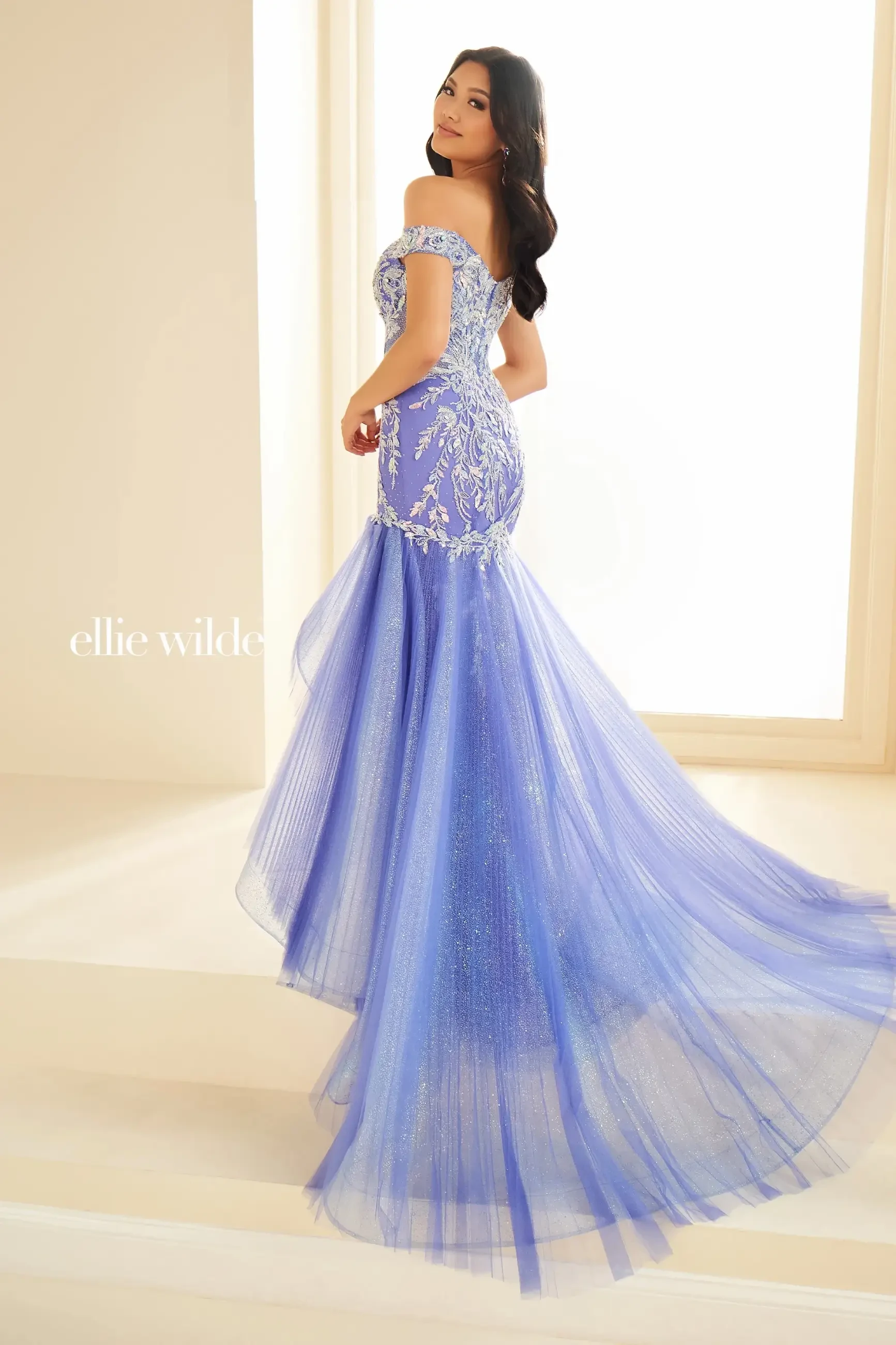 Model wearing a mermaid-style gown with a sweetheart neckline, off-the-shoulder sleeves, and sparkling sequin details.