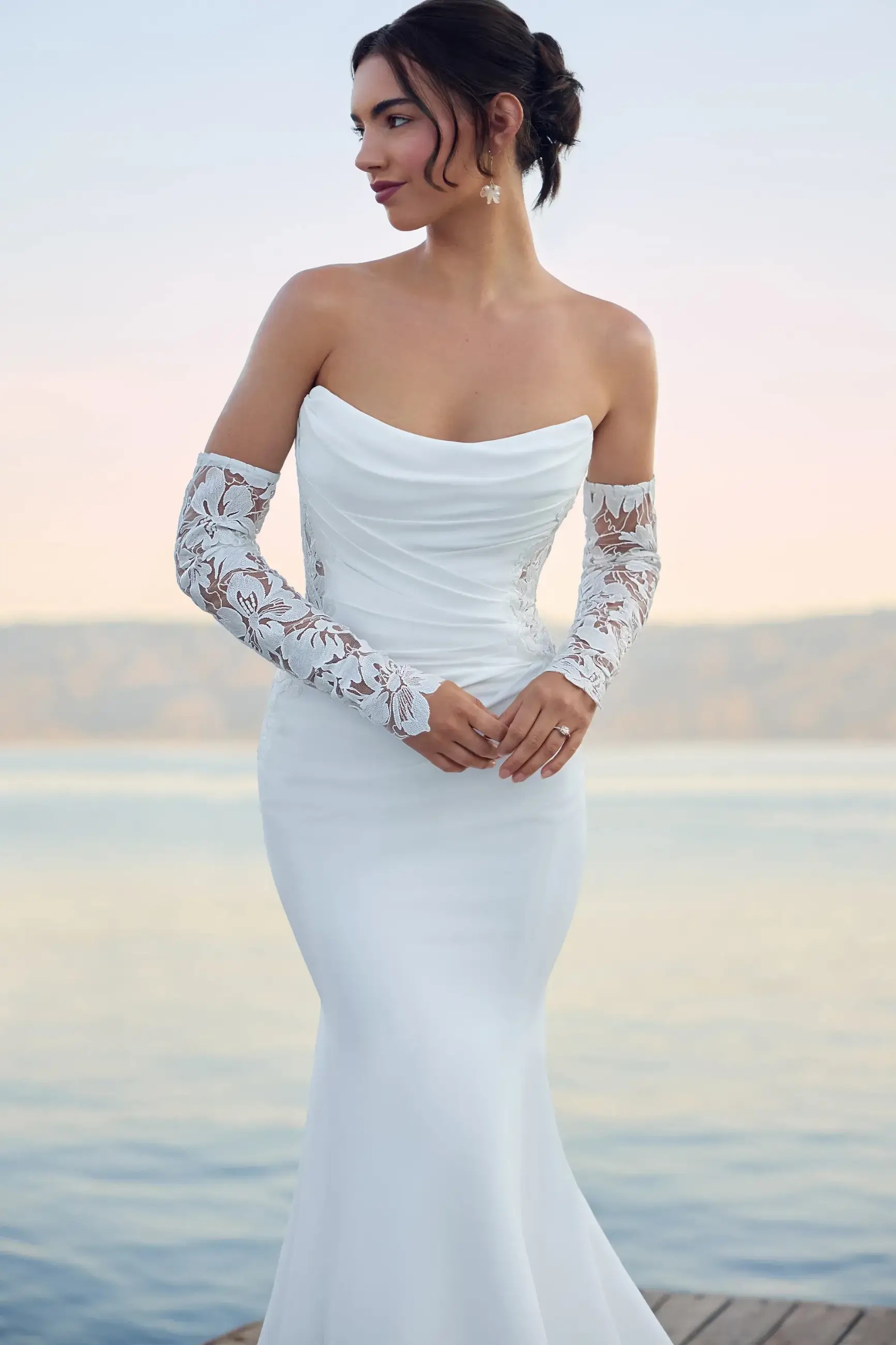 Model is wearing a crepe floral lace wedding dress with a scoop neckline by enchanting by mon cheri 