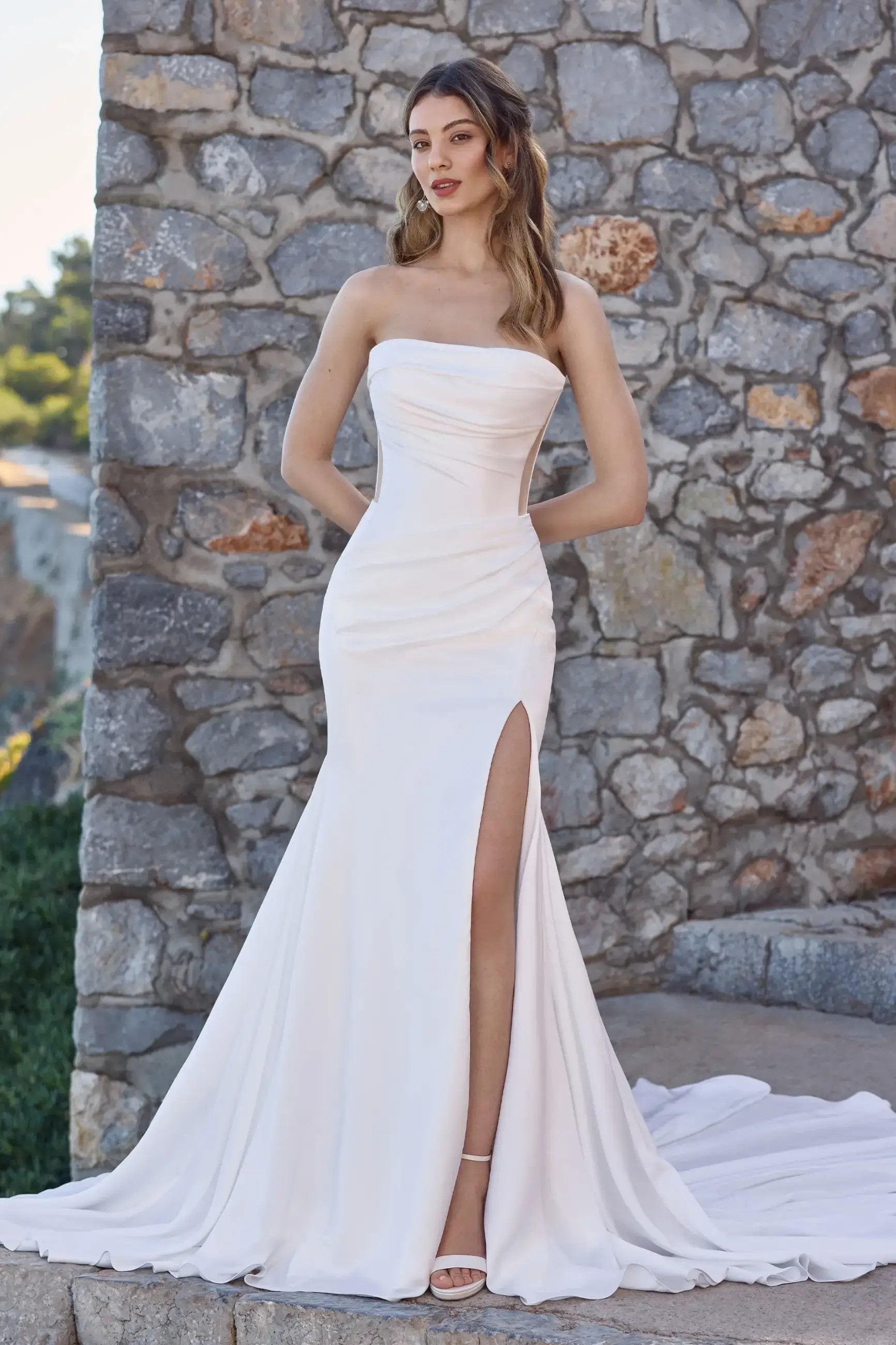 Model is wearing a satin fit and flare wedding dress by enchanting by mon cheri
