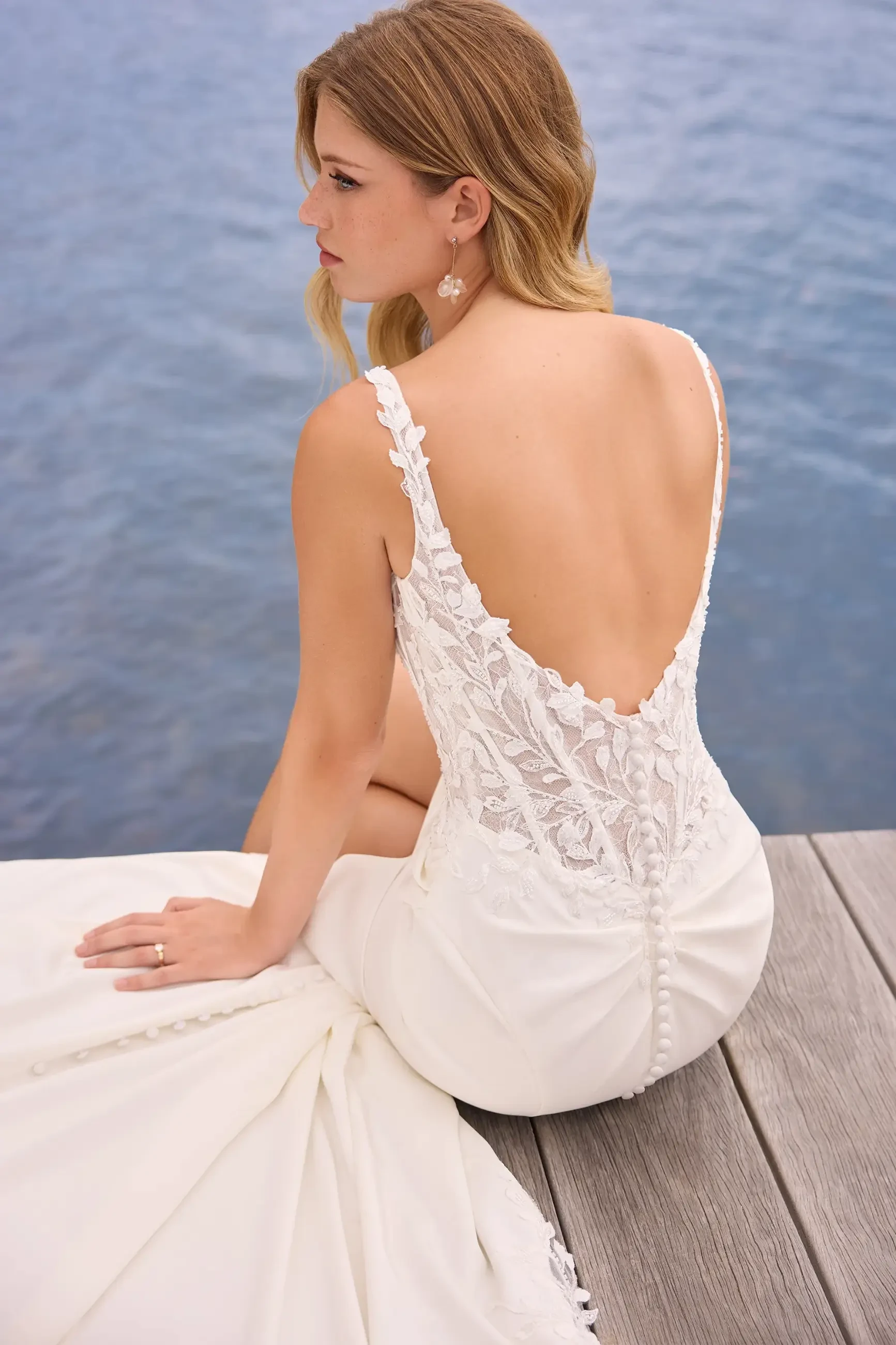 model is wearing a sleeveless open back fit and flare wedding dress